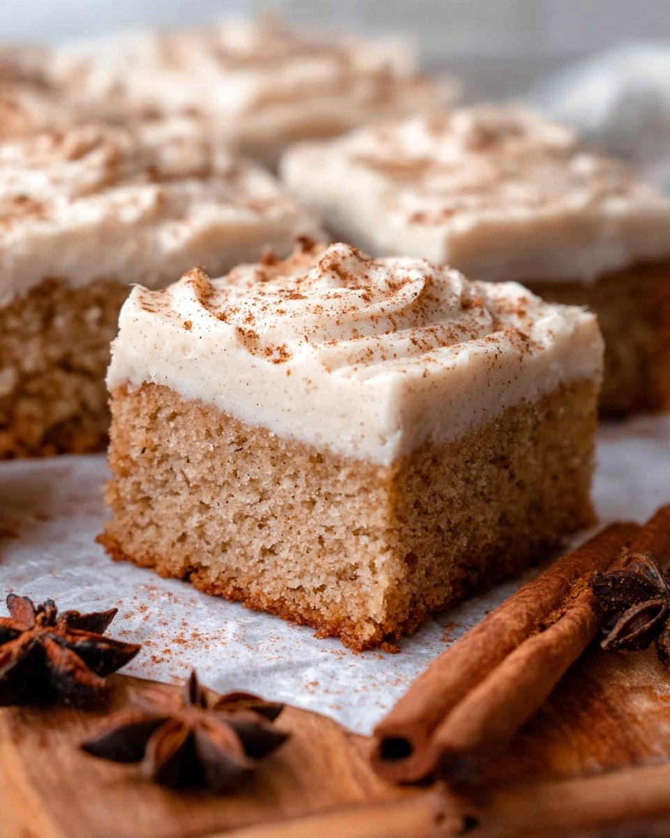 The image shows a close-up of moist spice cake squares arranged on a wooden surface with parchment paper underneath. Each square has two layers: the bottom layer is a dense, crumbly light brown cake with a slightly grainy texture, and the top layer is a thick, creamy white frosting sprinkled lightly with cinnamon powder. The cake edges are cleanly cut, showing the contrast between the soft frosting and the textured cake below. In the background and foreground, cinnamon sticks and star anise are placed as decoration, adding warm tones of brown and a natural rustic feel. The white marbled texture surface is visible around the wooden area. photo taken with an iphone --ar 4:5 --v 7