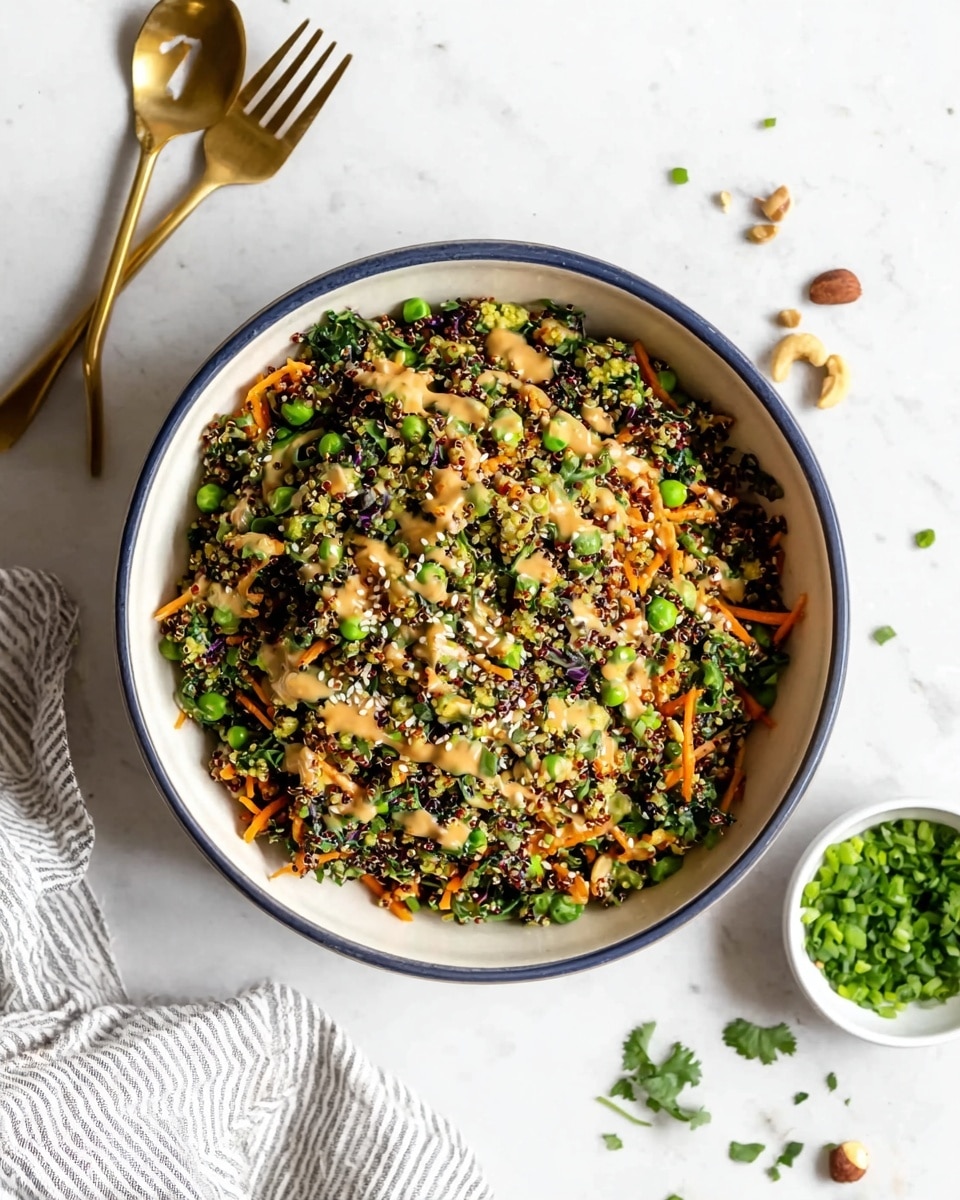 A bowl filled with a colorful quinoa salad showing multiple layers of small green peas, bright orange shredded carrots, finely chopped green onions, dark leafy greens, and scattered sesame seeds on top, all mixed together with a light brown creamy dressing drizzled unevenly. The bowl is white with a dark blue rim and sits on a white marbled texture surface. Around the bowl, there are small green herb leaves and some scattered nuts. A gold fork lies near the top left, and a small white bowl with green chopped herbs is placed near the bottom right. A white and gray striped cloth is partially visible at the bottom left photo taken with an iphone --ar 4:5 --v 7