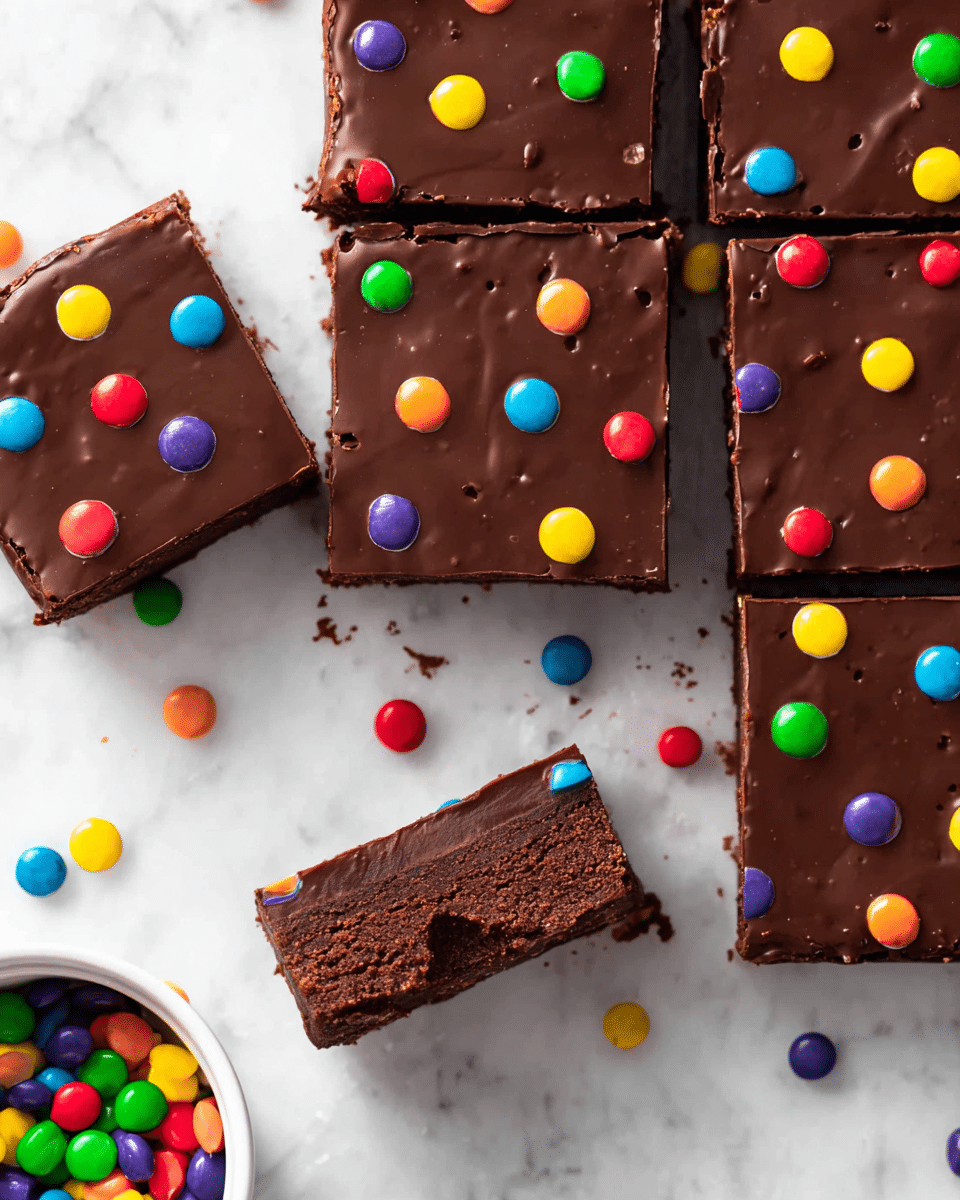 The image shows seven square slices of chocolate brownies arranged closely and spread out slightly on a white marbled surface. Each brownie has a smooth, shiny dark chocolate layer on top, decorated with small, colorful candy drops in red, green, yellow, purple, blue, and orange scattered evenly across the surface. One brownie near the center has a bite taken from its bottom right corner, revealing a rich, dense, dark brown interior layer below the chocolate topping. Extra colorful candy drops are scattered around the brownies on the white marbled surface, with a small white bowl filled with more candy drops partly visible in the bottom left corner. photo taken with an iphone --ar 4:5 --v 7