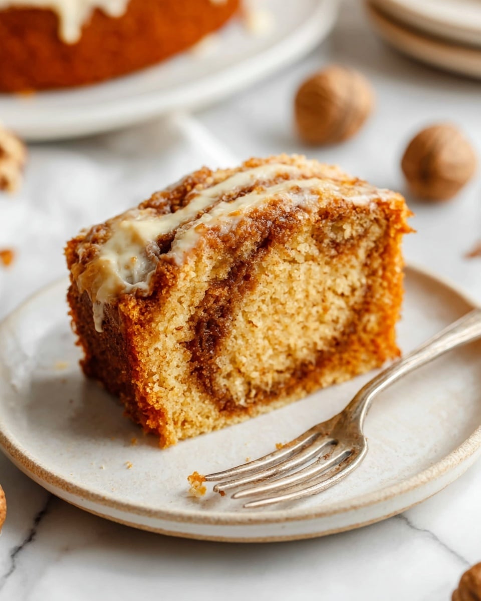 A single slice of cinnamon roll is placed on a simple white plate with a slight glossy finish. The cinnamon roll shows three visible layers: the outer golden-brown crust with a slightly crisp texture, the middle soft dough layer with light tan swirls of cinnamon sugar, and a thin, slightly glossy layer of cream cheese frosting lightly spread on top. A silver fork rests on the plate’s edge near the cinnamon roll, and a woman's hand holds the fork lightly from the right side. The background is a white marbled texture with a few blurred whole garlic bulbs and a piece of ginger placed softly behind the plate. Photo taken with an iphone --ar 4:5 --v 7