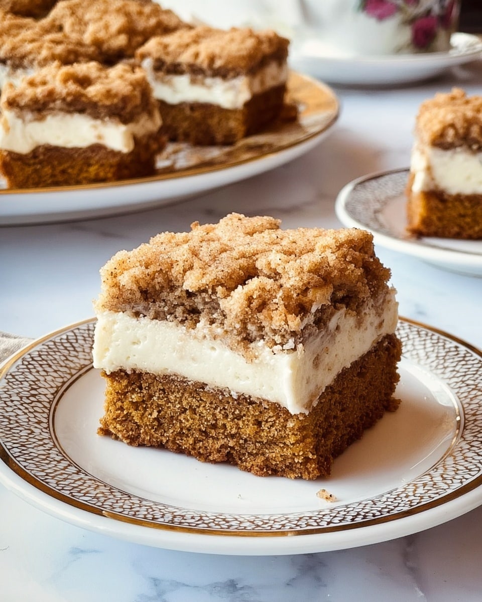 A close-up view of a square piece of crumb cake placed on a white plate with a thin grey patterned rim. The cake has three layers: a dense, light brown bottom layer, a thin creamy white middle layer, and a thick crumbly top layer with a mix of light and dark brown crumbs. Behind this plate, there is a larger white plate with four more pieces of the same cake, showing the same distinct layers and crumbly texture on top. All is set on a white marbled surface with a soft blue cloth in the background and some blurred small lights. Photo taken with an iphone --ar 4:5 --v 7