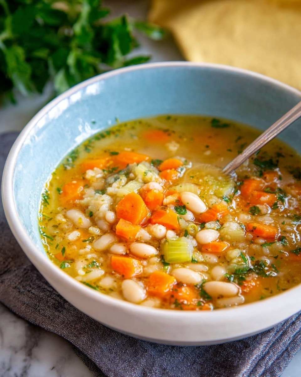 A white bowl filled with a warm soup that has three visible layers: a clear golden broth with small herbs floating on top, a middle layer with chunks of bright orange carrot pieces and light green celery, and a bottom layer dense with white beans scattered throughout. A silver spoon rests inside the bowl, partially submerged in the soup. The bowl sits on a gray cloth on a surface with a white marbled texture, with blurred green plants and a soft yellow background behind it. Photo taken with an iphone --ar 4:5 --v 7