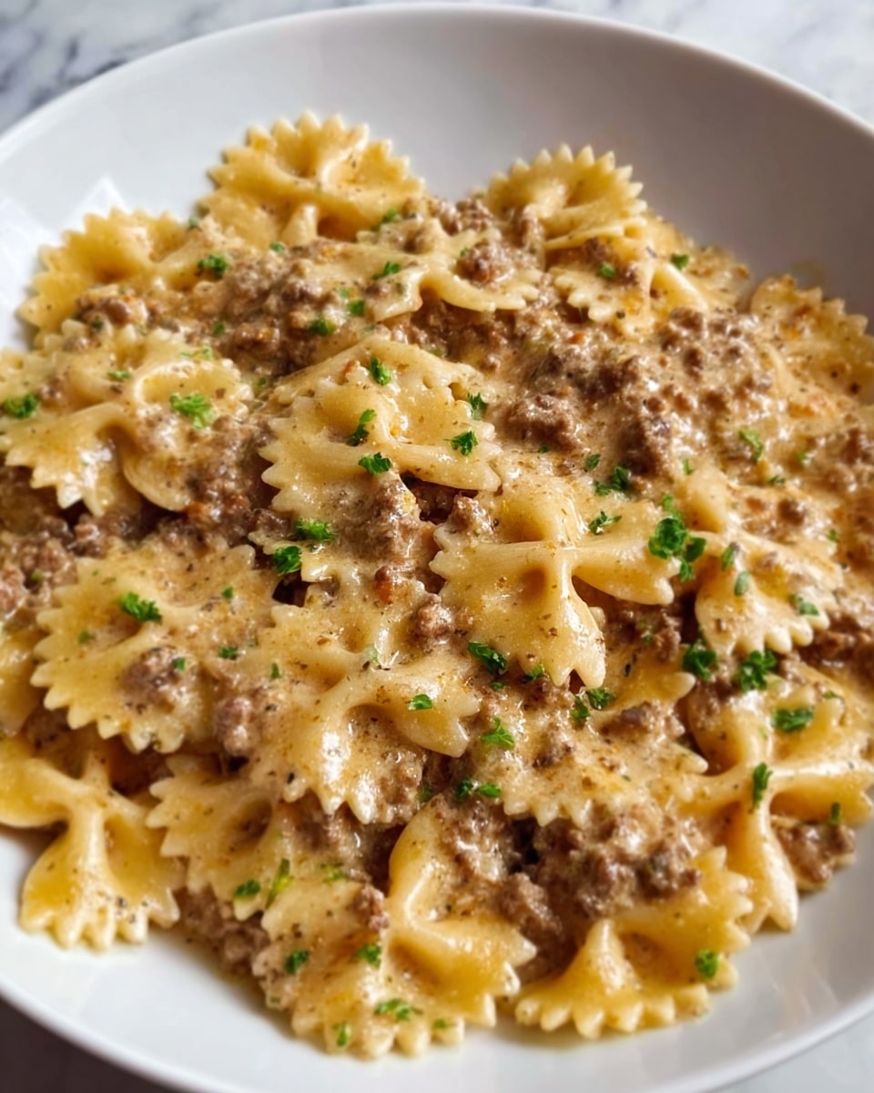 A white plate filled with farfalle pasta covered in a creamy, light brown meat sauce. The pasta shapes are clearly visible, ruffled and bow-tie like, sitting in a thick sauce with small bits of ground meat scattered evenly across the dish. There are small green herb leaves sprinkled lightly on top, adding a touch of color. The plate rests on a white marbled surface. photo taken with an iphone --ar 4:5 --v 7