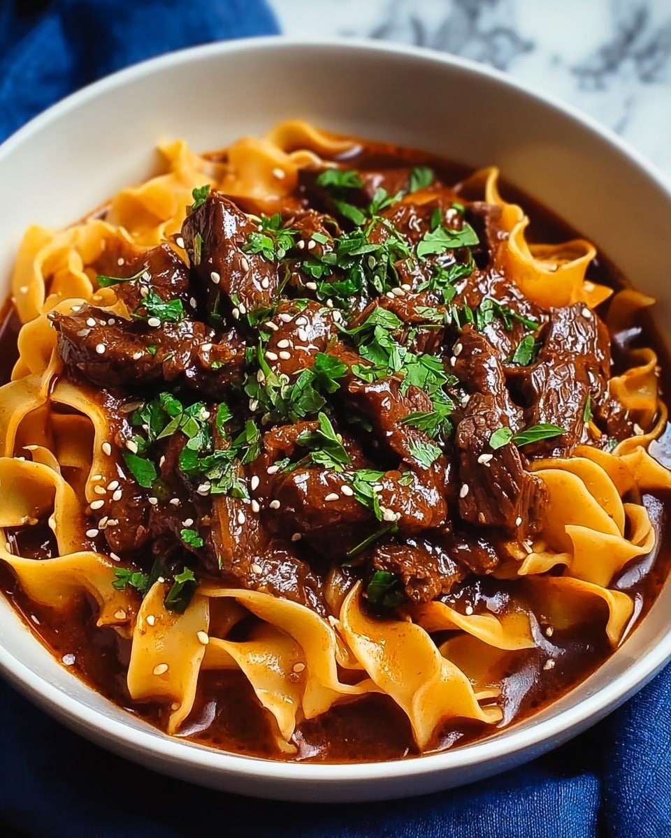 A white bowl filled with wide, flat yellow noodles forms the base layer, covered generously with a thick, dark brown stew made of beef strips. The beef is tender and coated in a rich sauce with a glossy texture, pooling slightly around the noodles. Small bits of white sesame seeds are sprinkled over the stew, along with fresh green chopped herbs scattered on top for color contrast. The bowl sits on a white marbled surface, capturing a warm, hearty meal. photo taken with an iphone --ar 4:5 --v 7