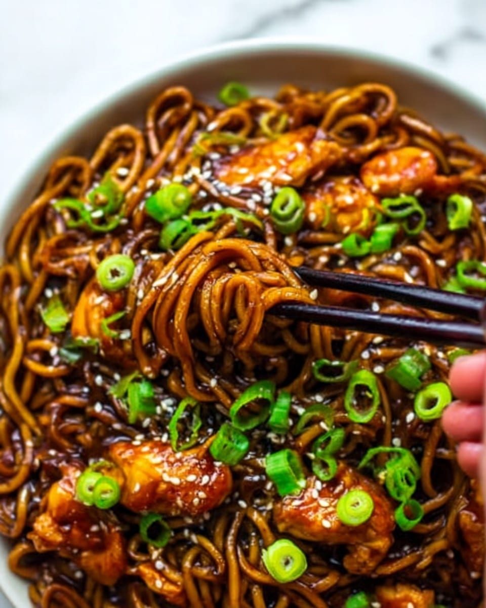 The image shows a close-up of a bowl filled with glossy, dark brown noodles, coated in a rich sauce. On top, there are pieces of cooked chicken with a caramelized shine, and small rings of bright green onions scattered evenly. White sesame seeds are sprinkled lightly over the dish, adding texture. A pair of black chopsticks held by a woman's hand is picking up some noodles and chicken. The bowl is white and placed on a white marbled surface. photo taken with an iphone --ar 4:5 --v 7