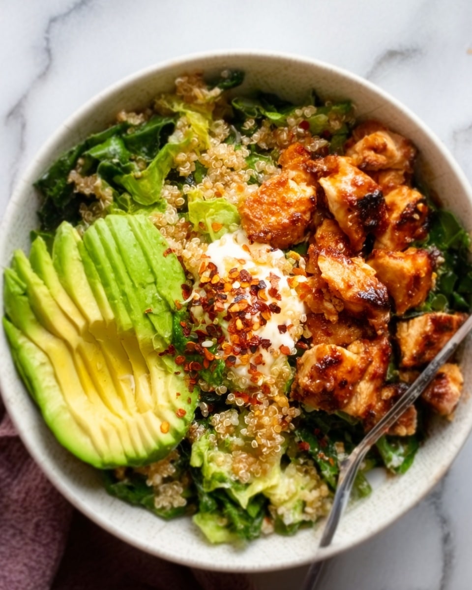 A white bowl filled with a layered salad is shown. The bottom layer is a mix of green leafy vegetables with a rough texture. On top are small, golden-brown chunks of grilled chicken with a slightly crispy surface, adding texture and color contrast. To one side, thin slices of bright green avocado fan out smoothly. A dollop of creamy white sauce is placed near the chicken, topped with a sprinkle of chili flakes adding a deep red color. A woman's hand holds a fork near the bowl, ready to eat. The whole scene is set on a white marbled surface. photo taken with an iphone --ar 4:5 --v 7