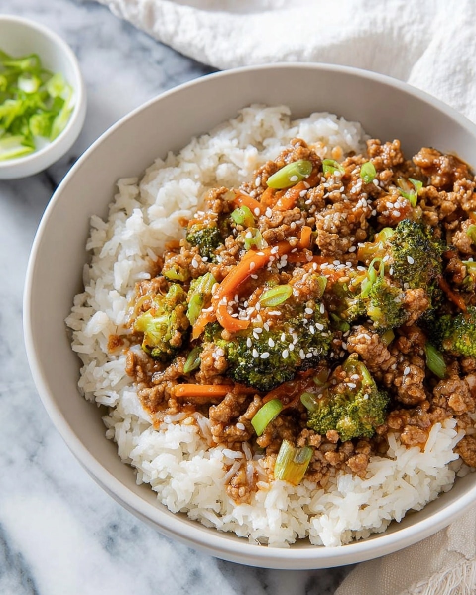 A light grey bowl sits on a white marbled surface, filled with two layers: the bottom layer consists of fluffy, light brown cooked rice with a soft texture, and the top layer is a colorful stir-fry mix of ground meat, thin orange carrot slices, green broccoli pieces, and dark brown sauce-coated vegetables. The stir-fry is sprinkled with white sesame seeds and small bits of bright green chopped green onion, adding texture and color contrast. A white cloth is visible beside the bowl. photo taken with an iphone --ar 4:5 --v 7
