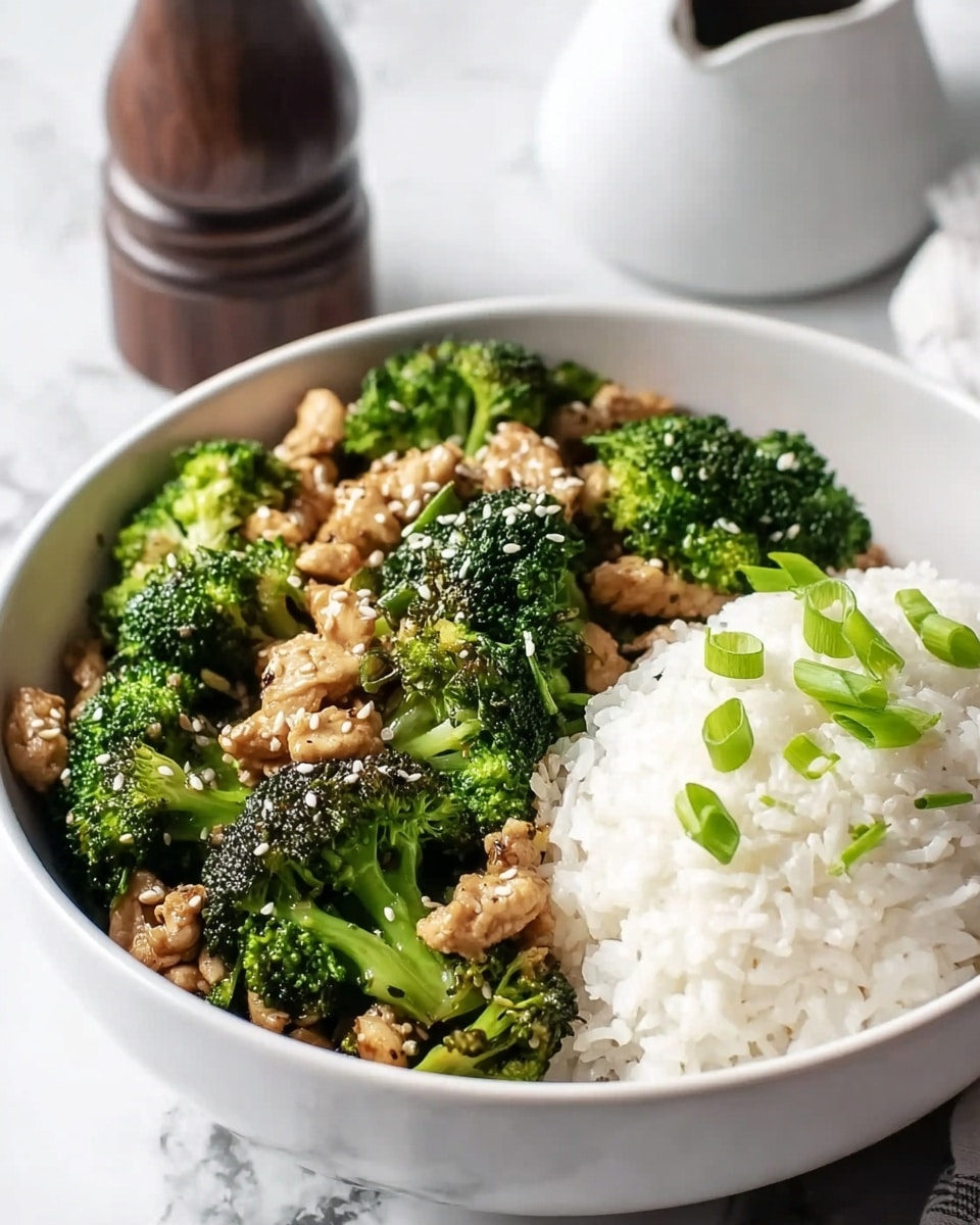 A white bowl filled with two main layers: one half has bright green broccoli florets cooked with small pieces of brown chicken, topped with white sesame seeds, while the other half has a neat mound of white rice sprinkled lightly with sliced green onions. The bowl sits on a white marbled surface, with a blurred pepper grinder in the background. Photo taken with an iphone --ar 4:5 --v 7