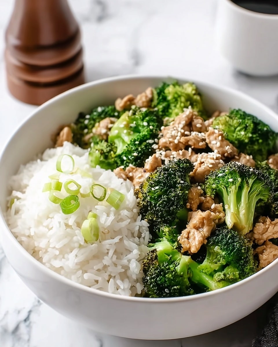 A white bowl filled half with bright green broccoli florets mixed with small pieces of brown cooked chicken, topped with white sesame seeds and thin slices of green onion. The other half of the bowl has fluffy white rice garnished with a few pieces of green onion. The bowl sits on a white marbled surface with a soft, natural light that highlights the textures and colors. Photo taken with an iphone --ar 4:5 --v 7